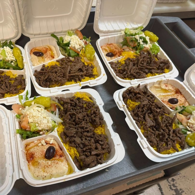 Multiple Cairos Gyros Tempe takeout containers filled with gyro meat, yellow rice, salad, and hummus.